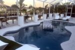 Heated saltwater pool with lounger and canal view at sunset — Canal Villa, Port Charlotte