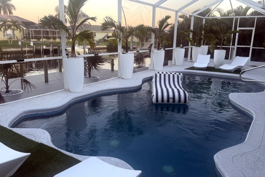 Heated saltwater pool with lounger and canal view at sunset — Canal Villa, Port Charlotte