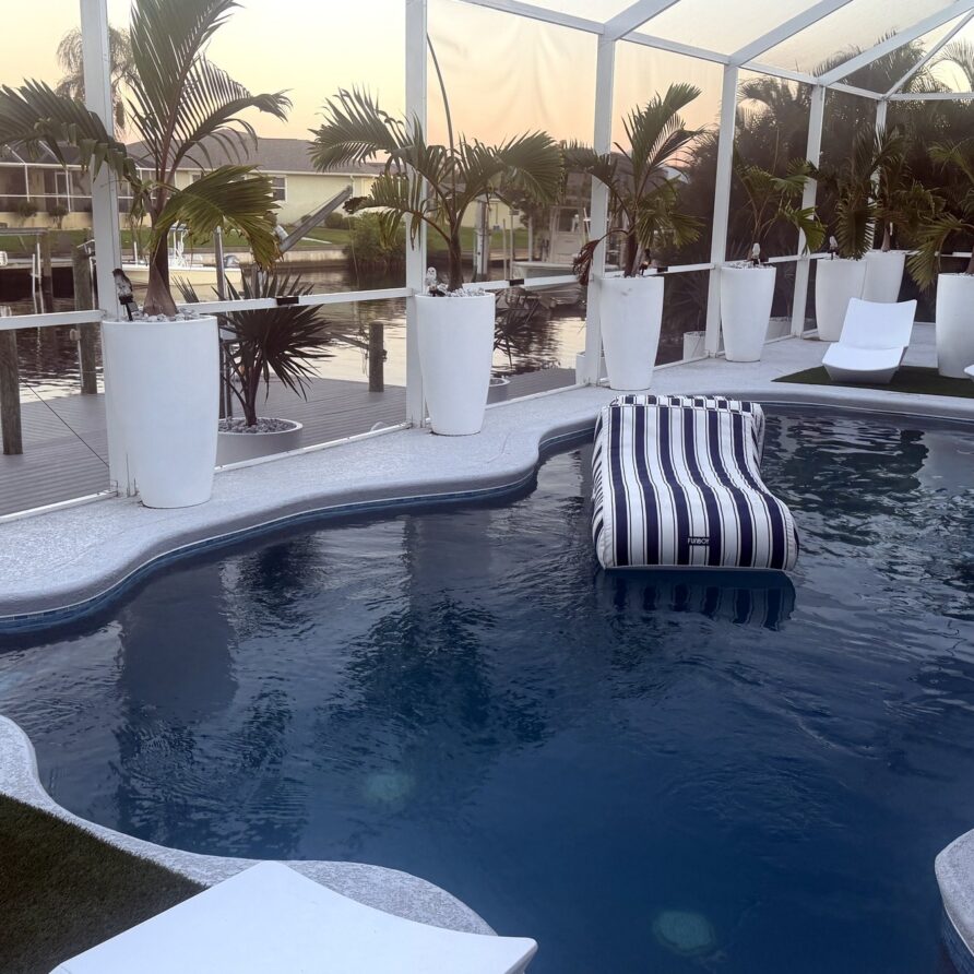 Heated saltwater pool with lounger and canal view at sunset — Canal Villa, Port Charlotte