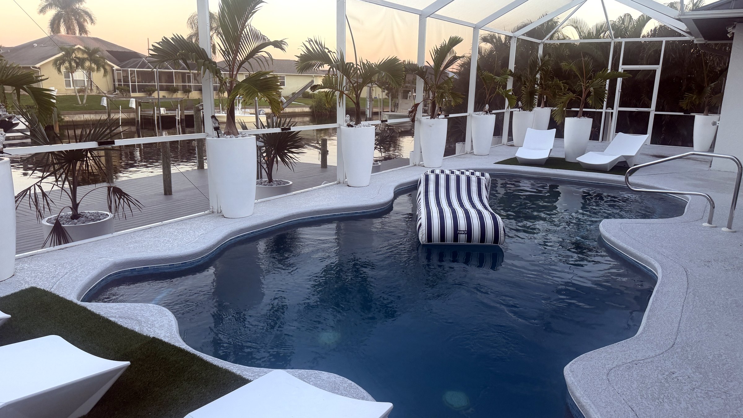 Heated saltwater pool with lounger and canal view at sunset — Canal Villa, Port Charlotte