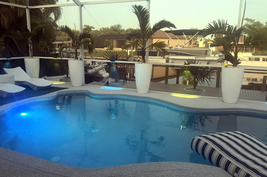 Pool lit blue at dusk under the screened lanai — Canal Villa