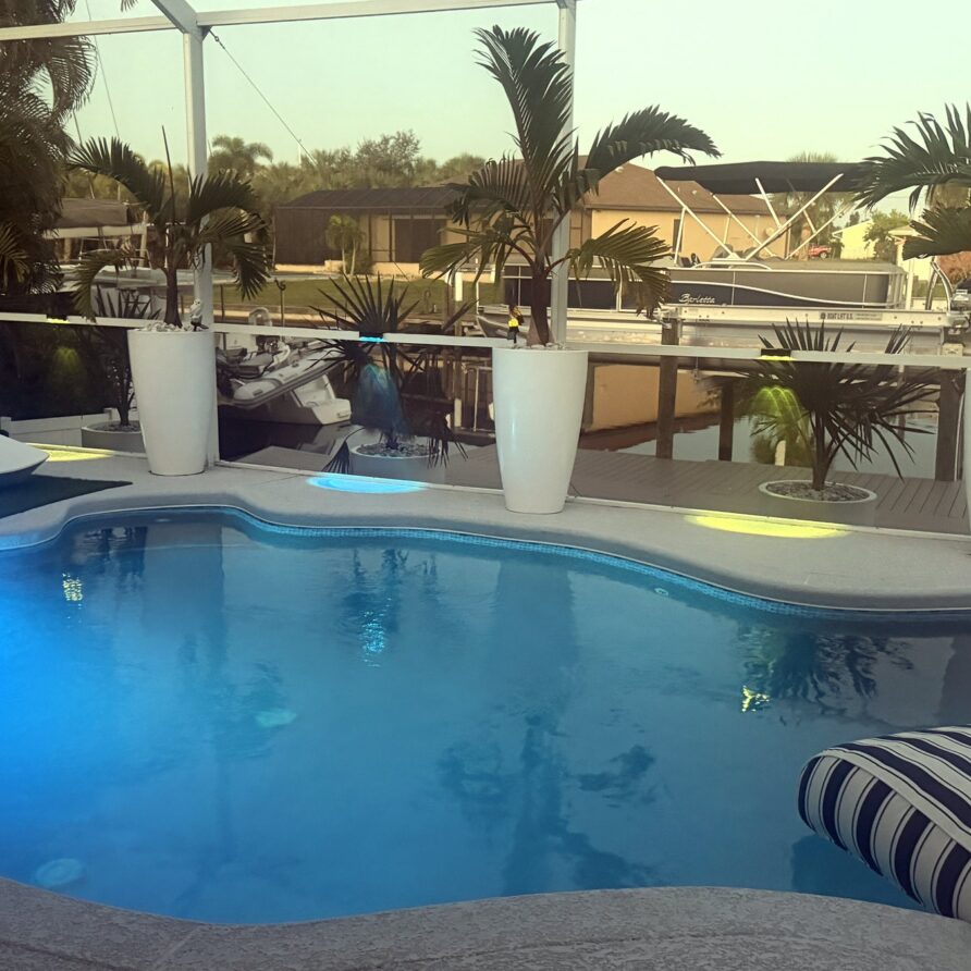 Pool lit blue at dusk under the screened lanai — Canal Villa