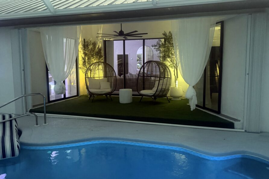 Lanai lounge with hanging egg chairs lit at night — Canal Villa