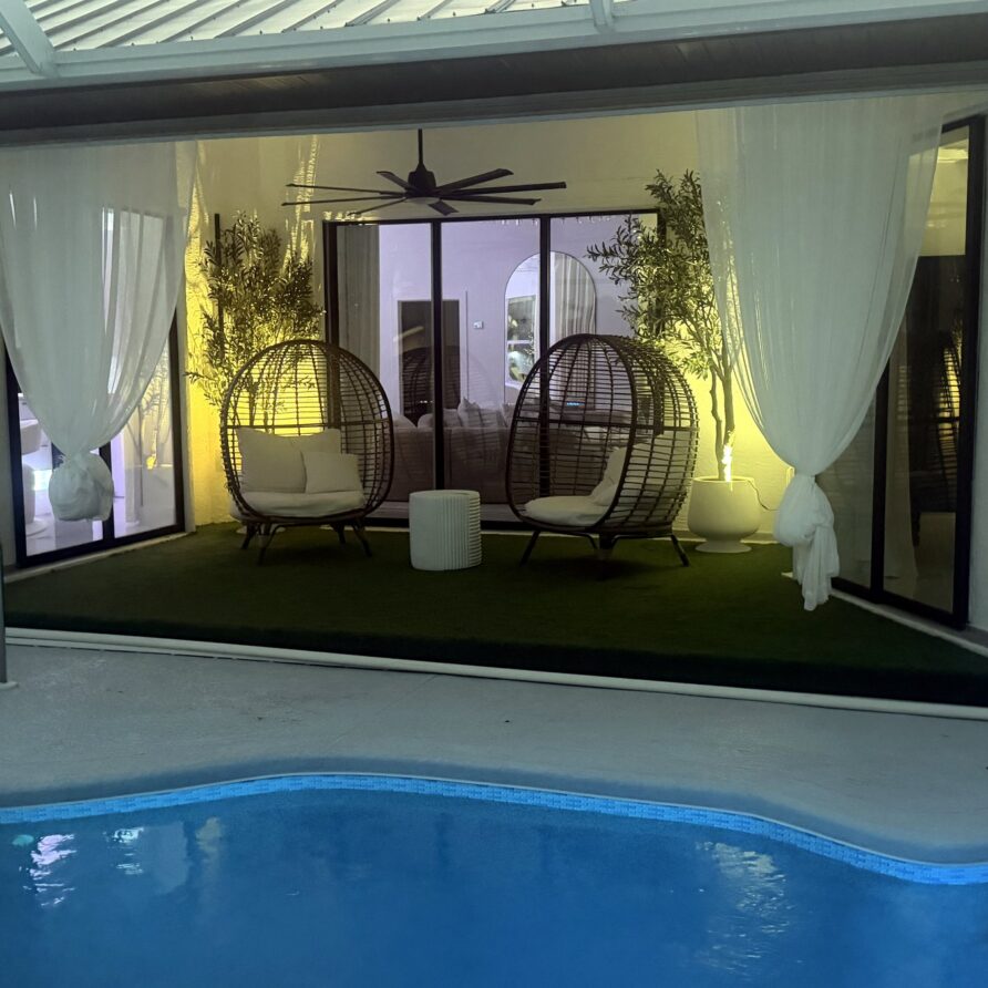 Lanai lounge with hanging egg chairs lit at night — Canal Villa