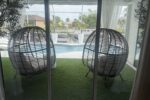 Screened lanai with egg-chairs opening to the pool and canal