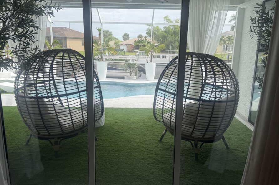 Screened lanai with egg-chairs opening to the pool and canal