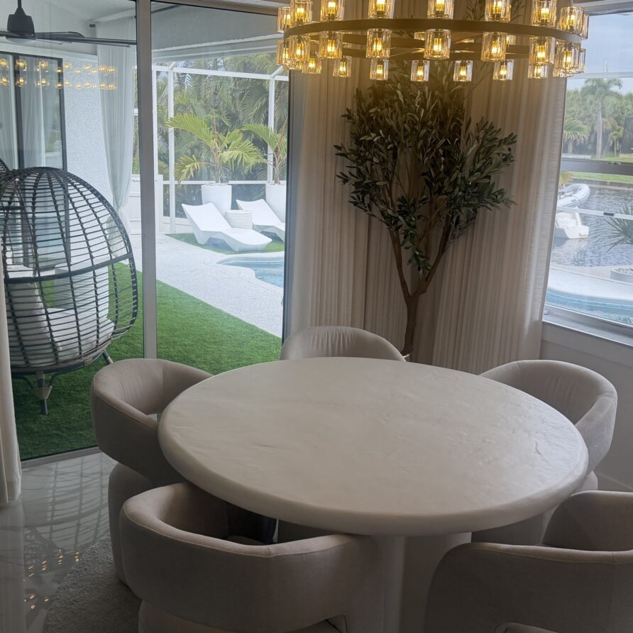 Open-plan kitchen looking past the dining table to the pool and the canal beyond.