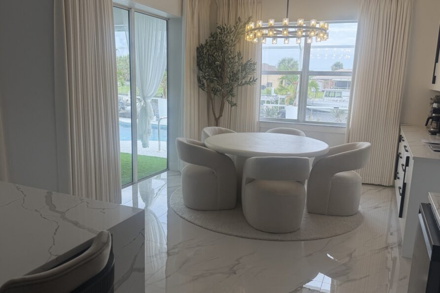 Dining area with water on both sides - pool through one wall of glass, canal through the other.