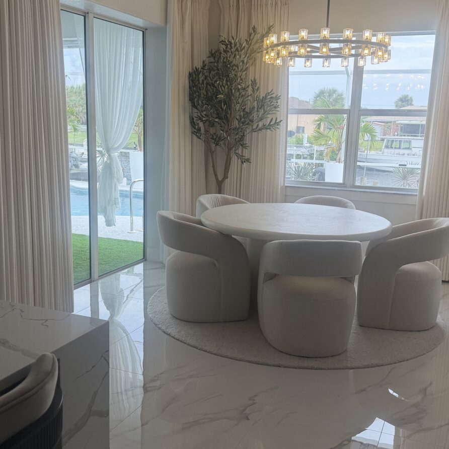 Dining area with water on both sides - pool through one wall of glass, canal through the other.